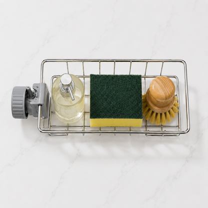 Overhead view of the rack on a marble counter holding a glass soap dispenser, a green and yellow sponge and a wooden dish brush